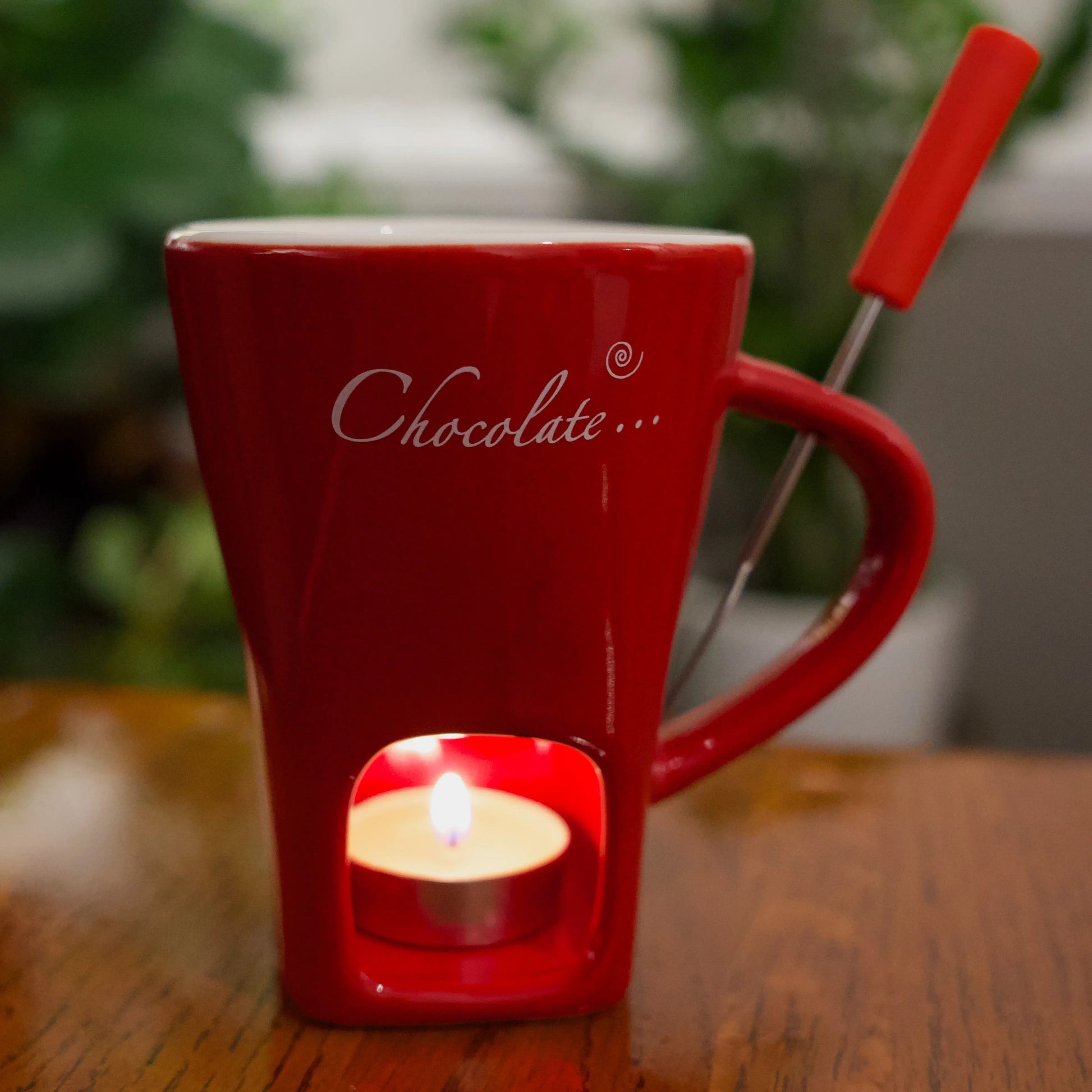 Red mug with a built-in candle holder on a wooden surface