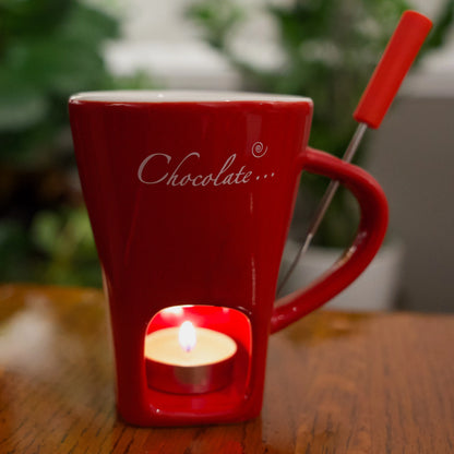 Red mug with a built-in candle holder on a wooden surface